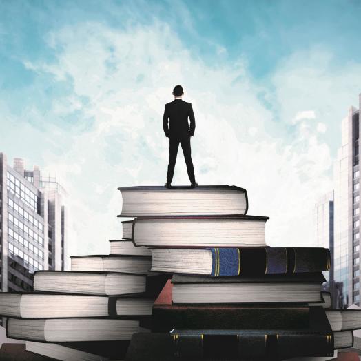 Man standing confidently on top of a tower of books